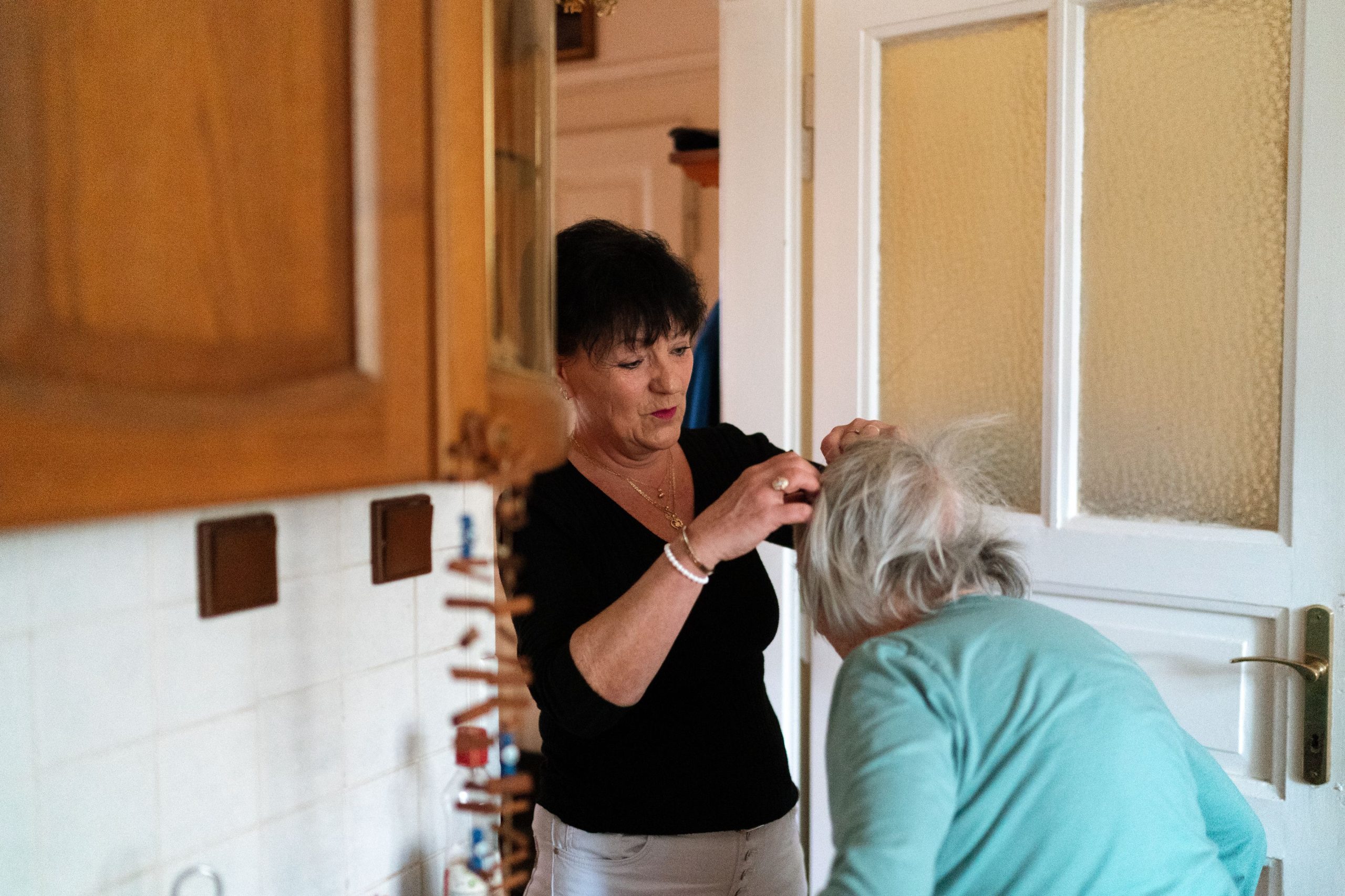 Betreuungskraft begrüßt eine Seniorin an der Haustür