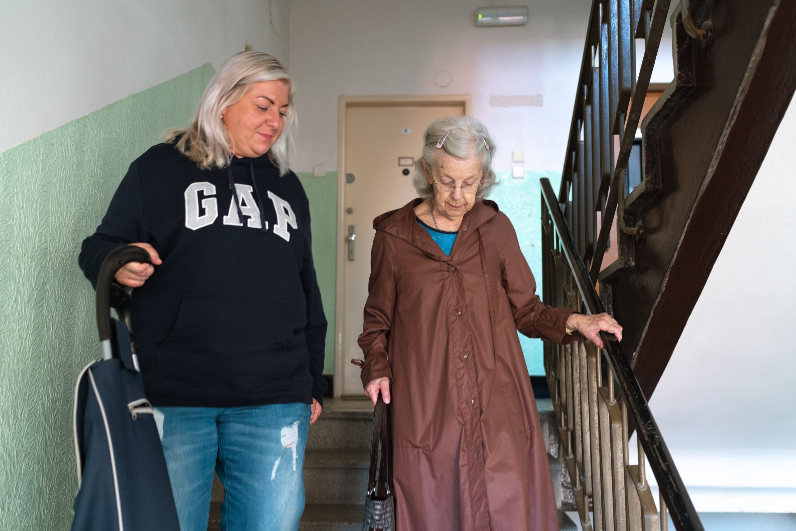 Pflegekraft unterstützt Seniorin sicher auf der Treppe