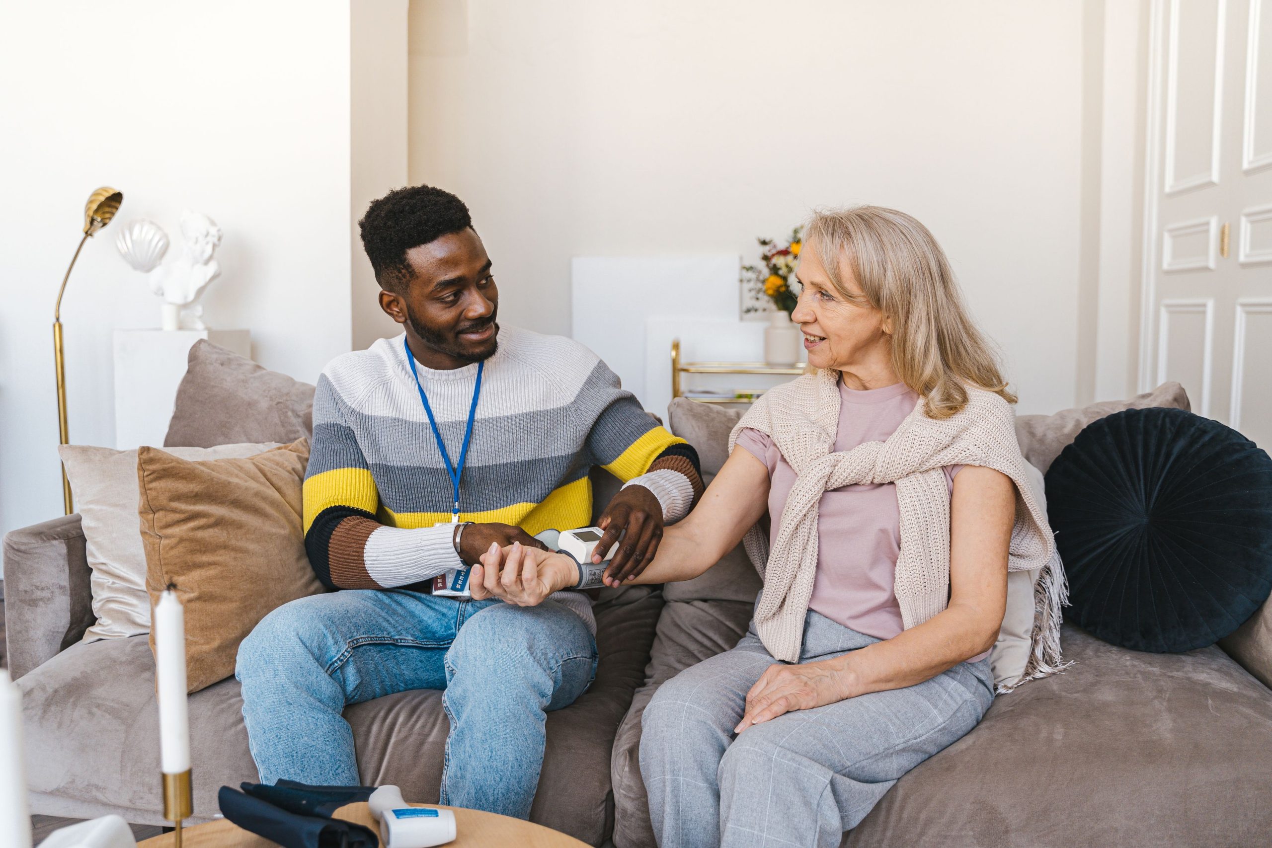 Betreuungskraft im Gespräch mit einer Seniorin auf dem Sofa
